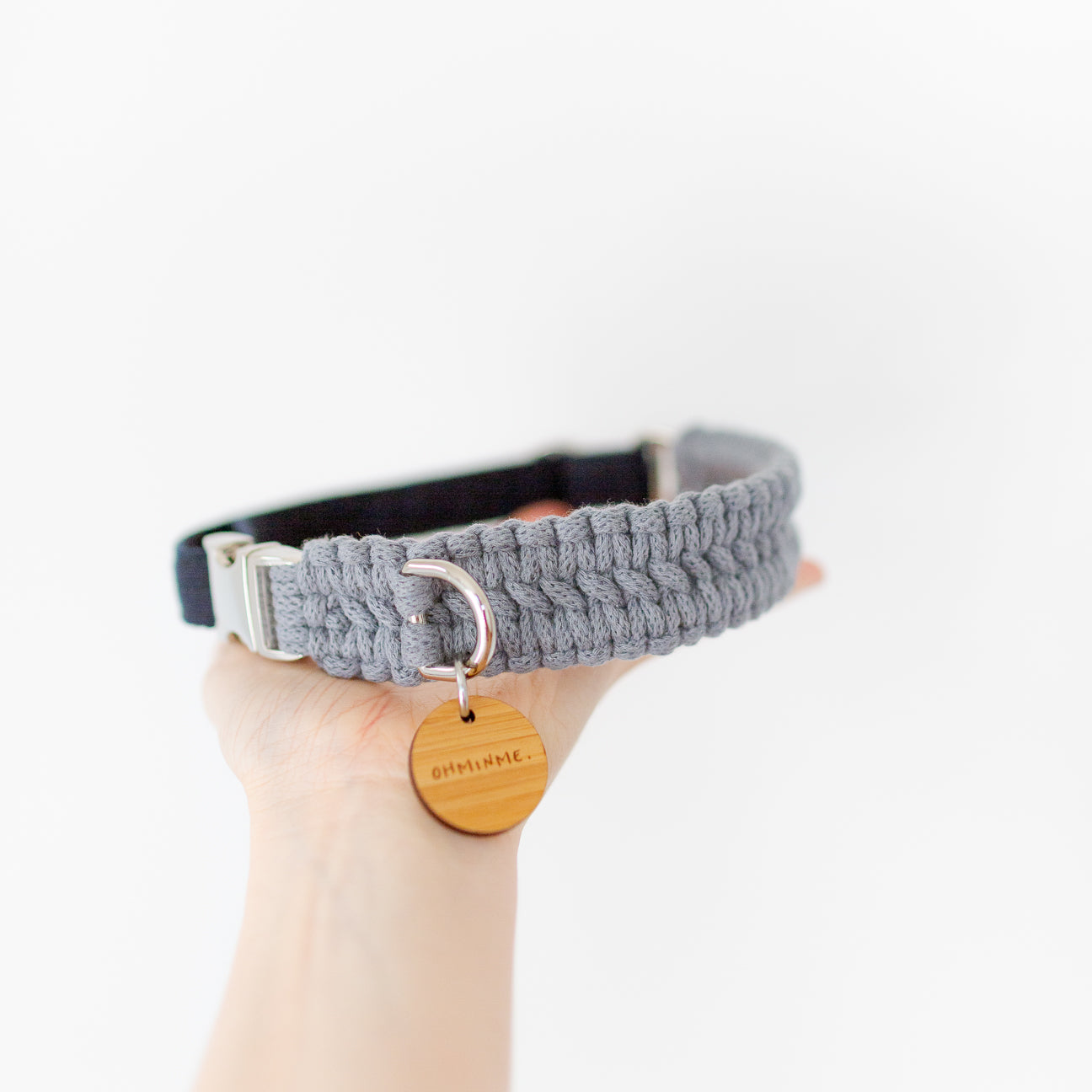 hand holding a macrame dog collar in grey and navy with a bamboo tag