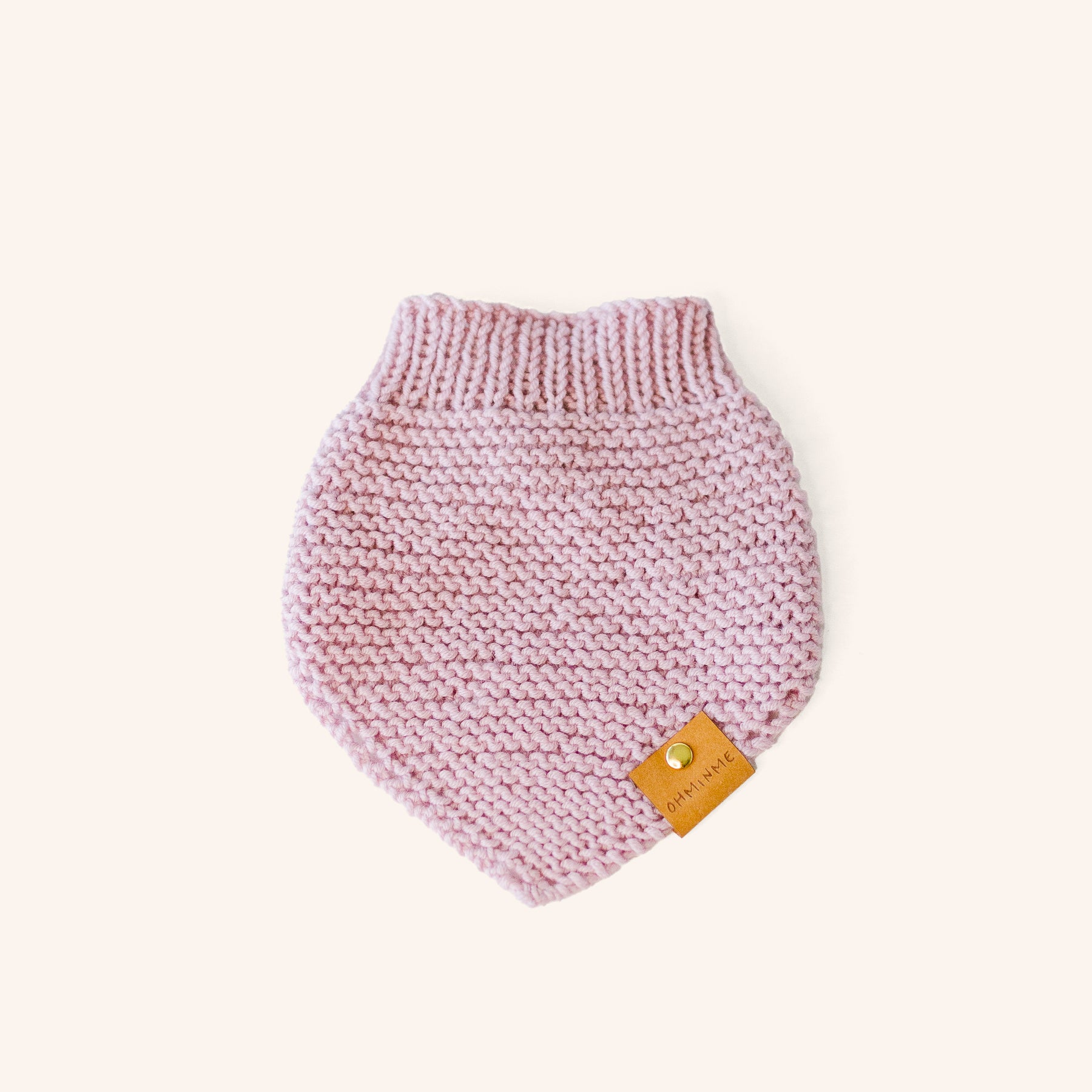 knitted baby pink merino wool pet bandana with a brown paper label and brass rivet