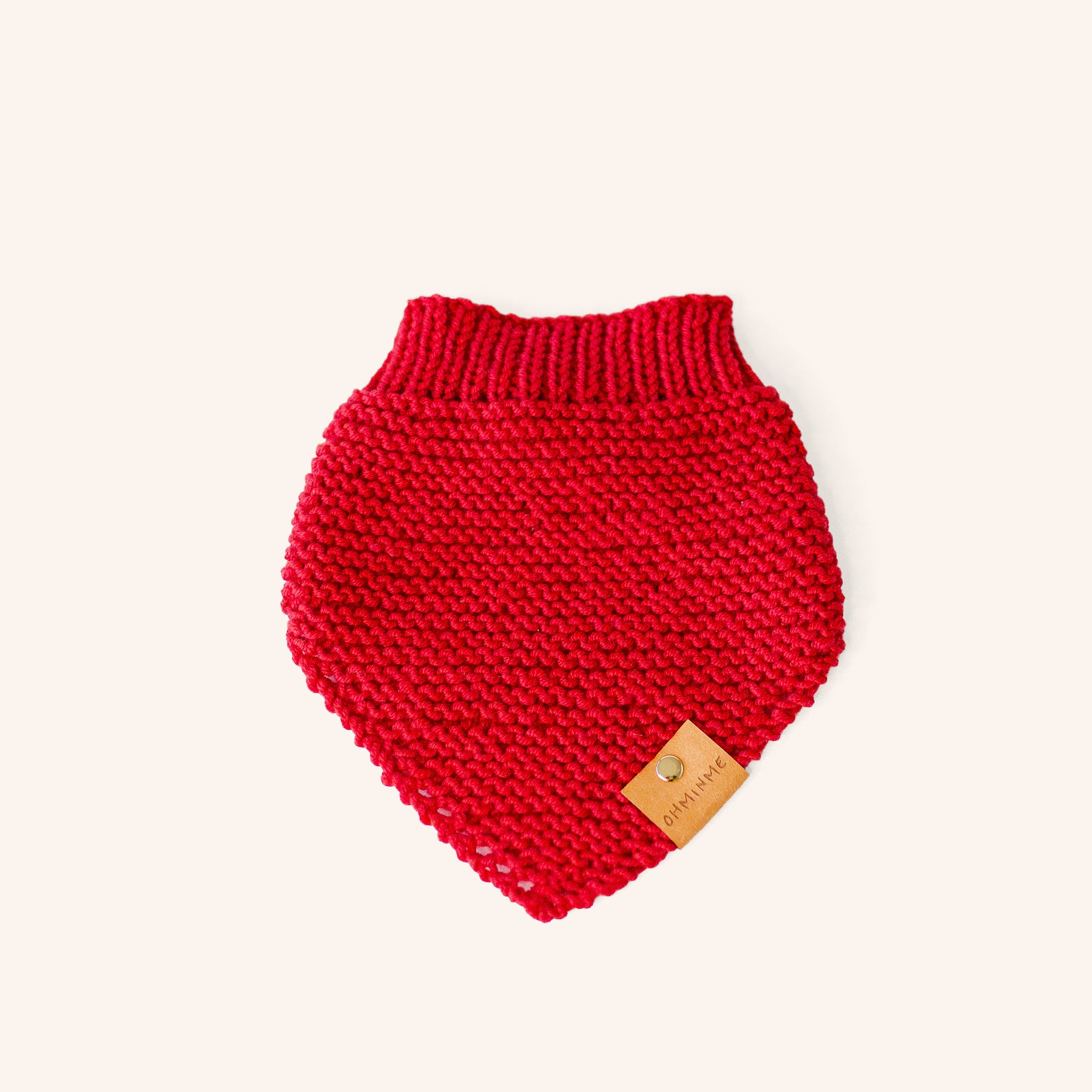 knitted wool pet bandana in a cheerful red colour with a brown OHMINME label and brass rivet
