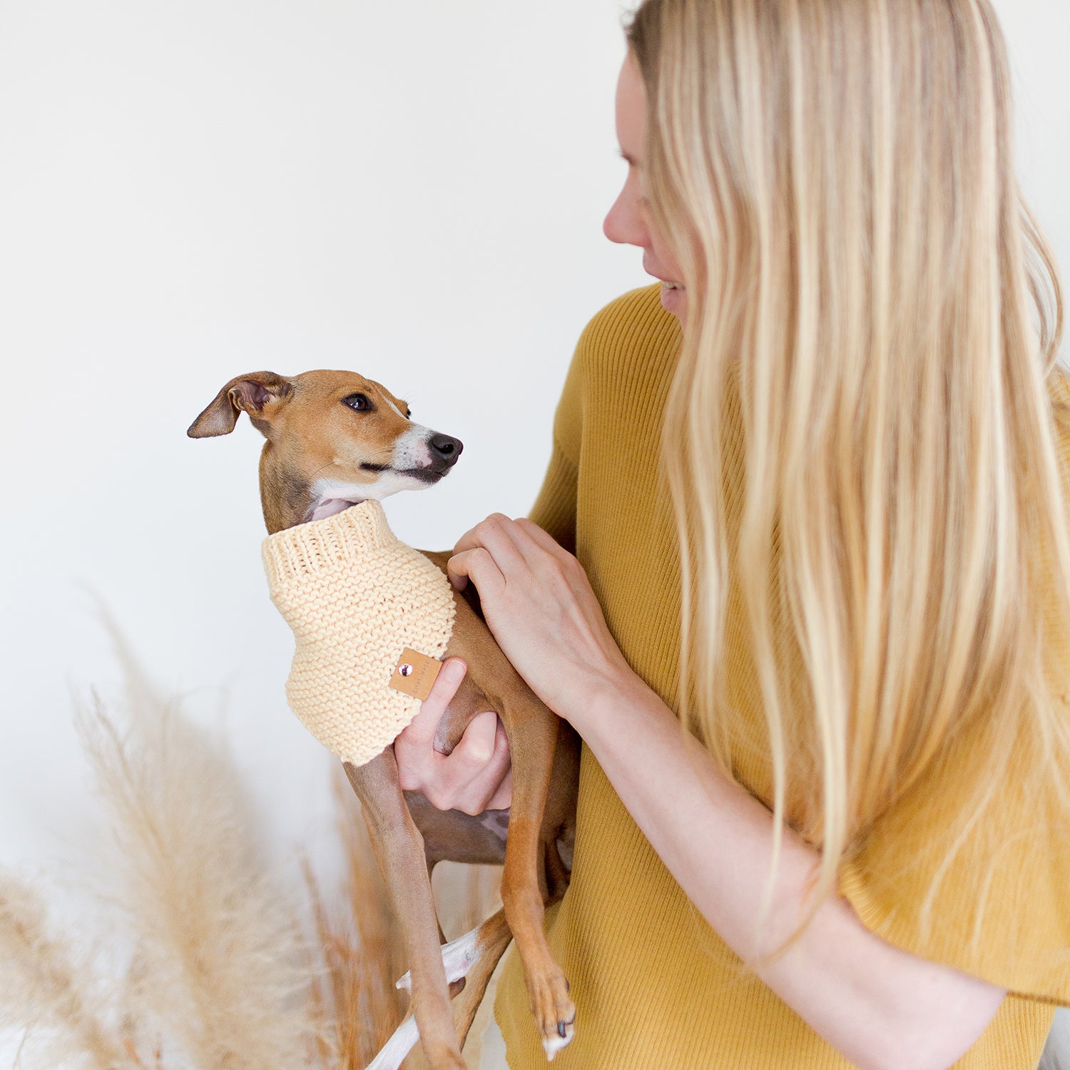 woman with long blonde hair in yellow shirt holding red italian greyhound wearing yellow organic wool dog bandana