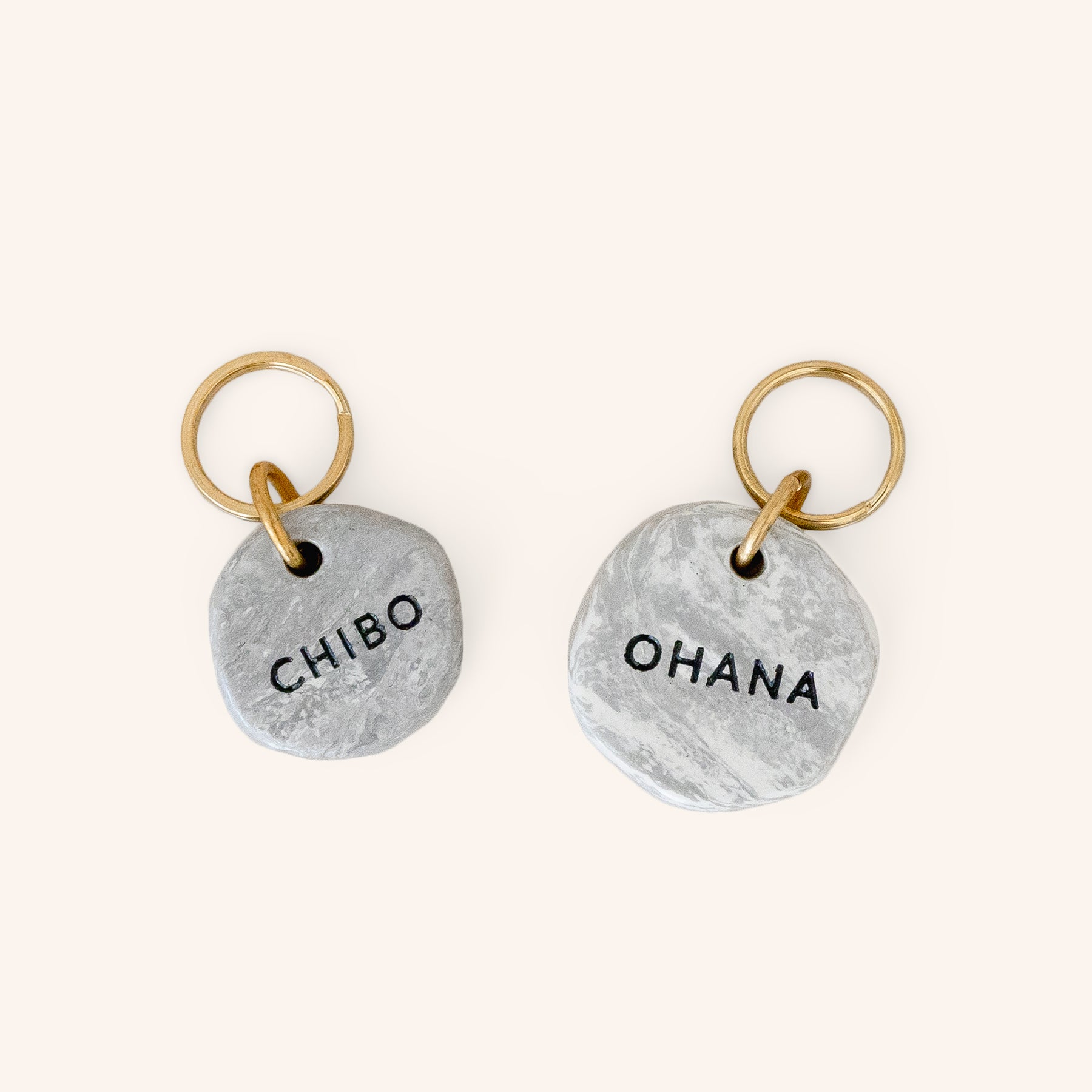 small and large marble look pet ID tags engraved with custom name and brass split ring, close-up