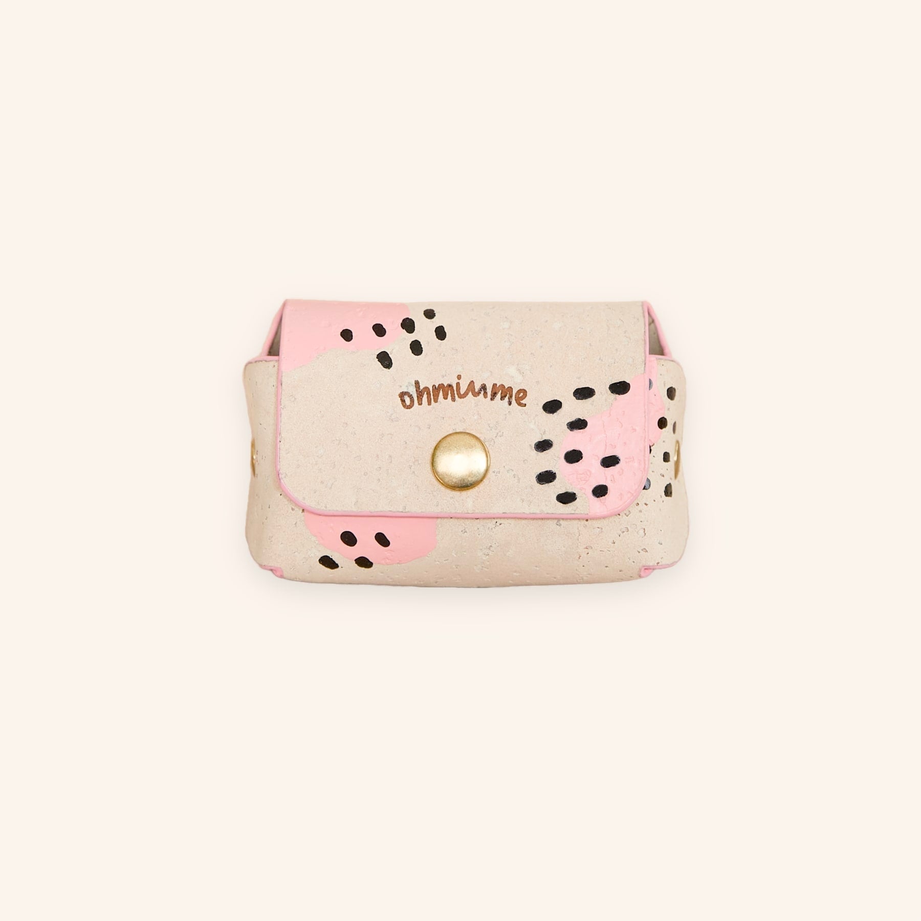 Cream beige dog poop bag holder with pink accents and black dots in cork leather, front view.