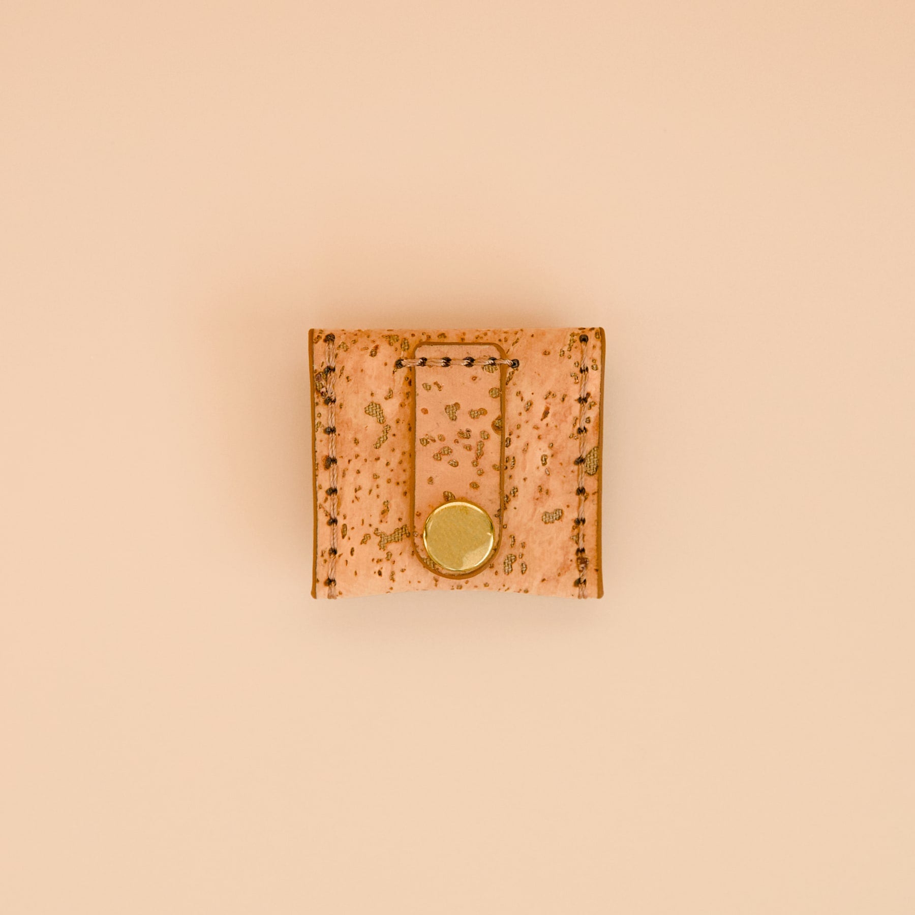 Mocha brown cork dog AirTag holder with brass details, back view