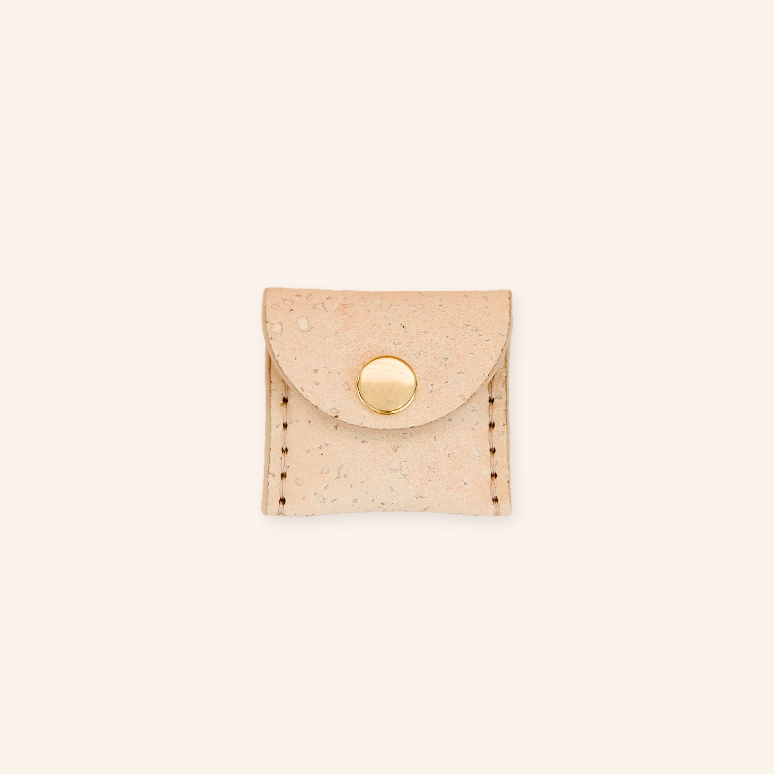 Dog airtag holder in cream beige cork leather with a brass button, front view.