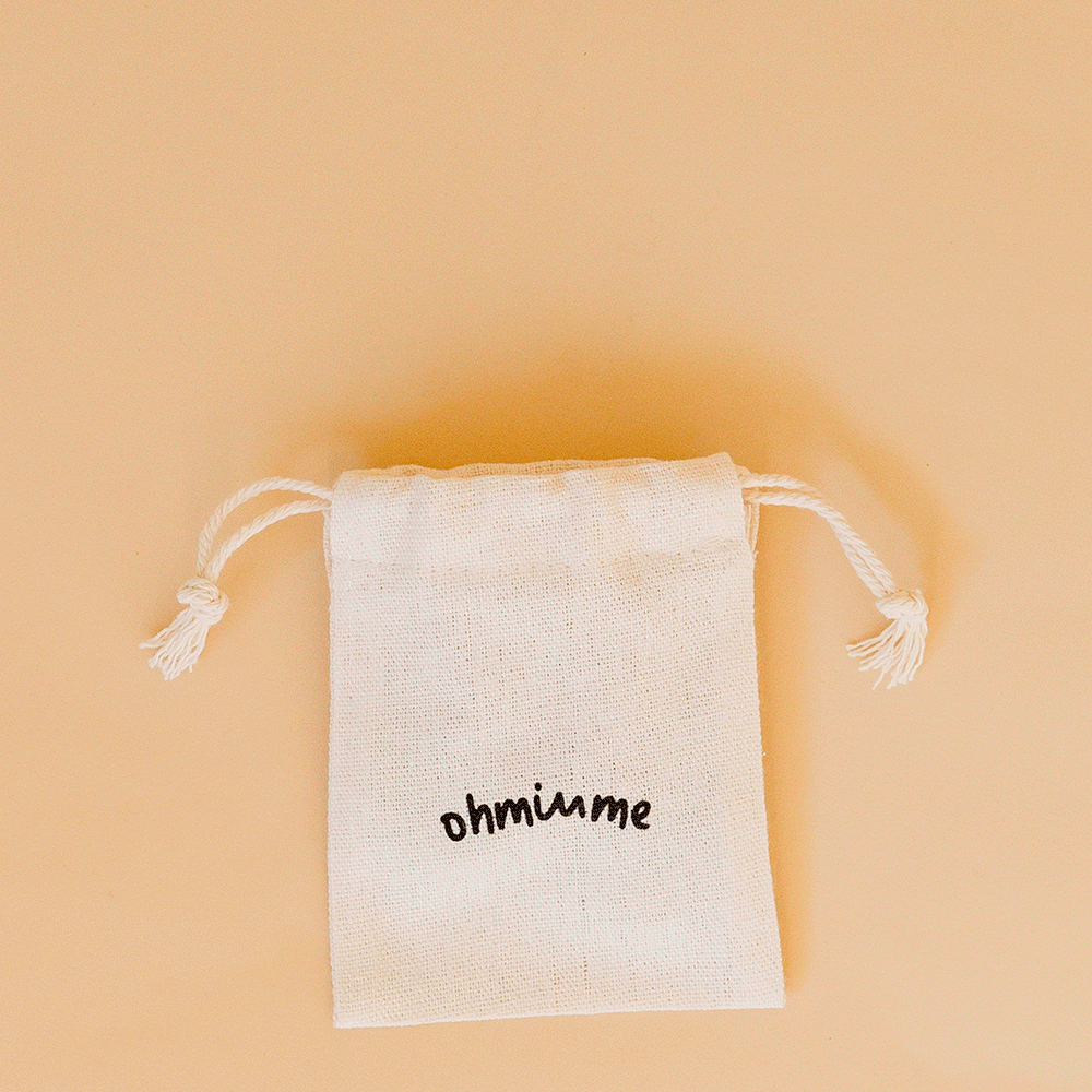 Personalised dog name tags moving in and out of a linen drawstring bag