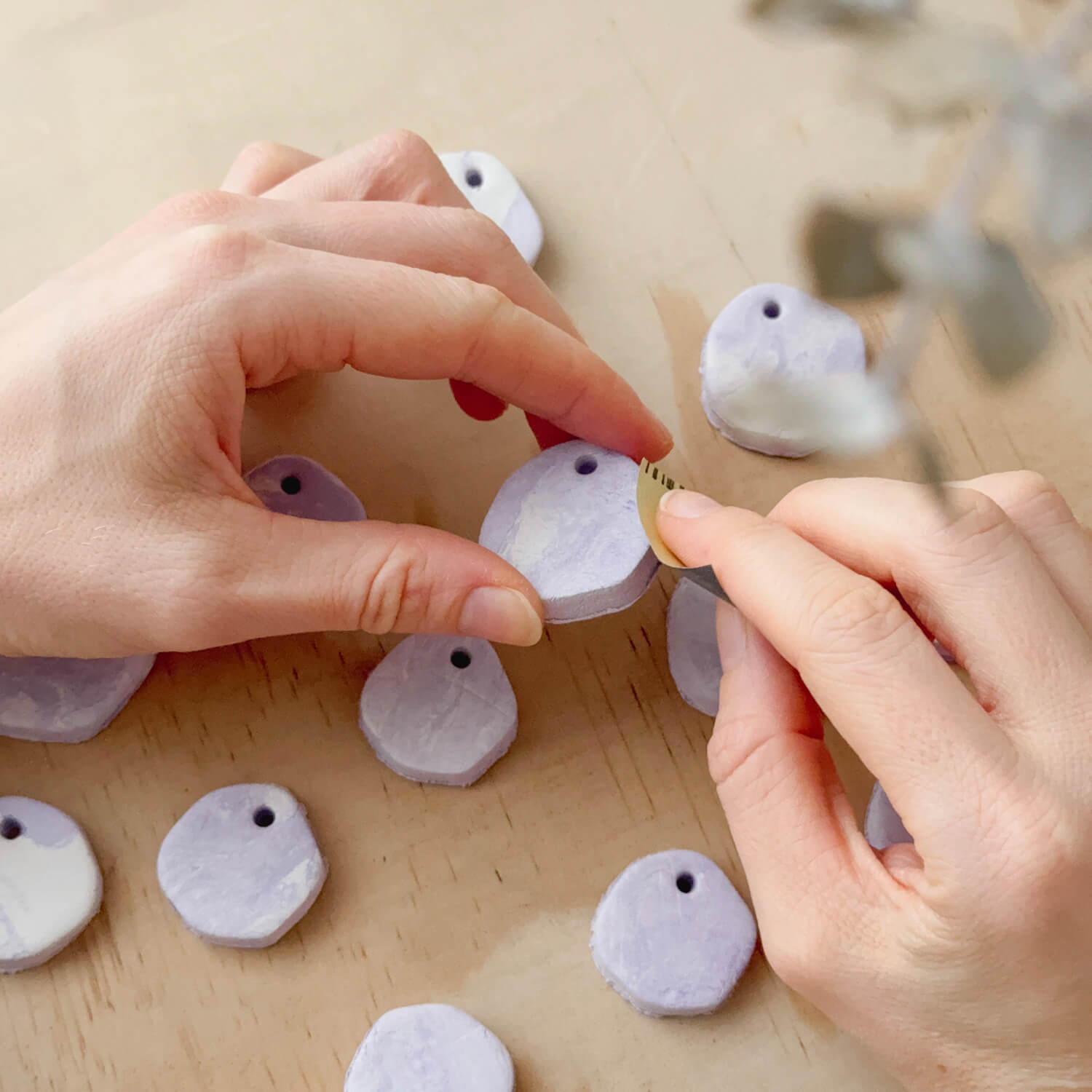 Purple marble-look dog name tags being sanded by hand