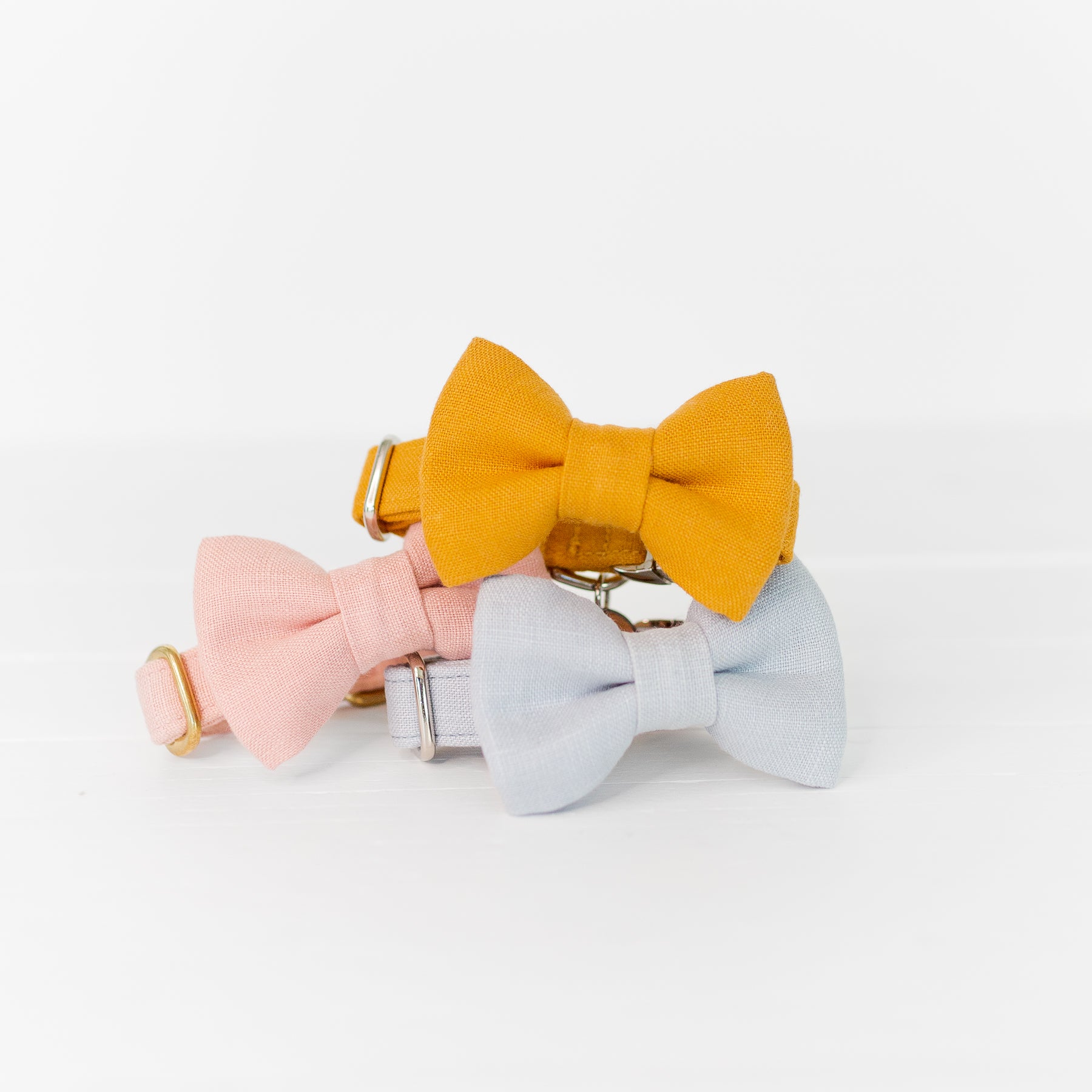 Dog bow tie collars in pastel pink, blue, and mustard yellow linen.