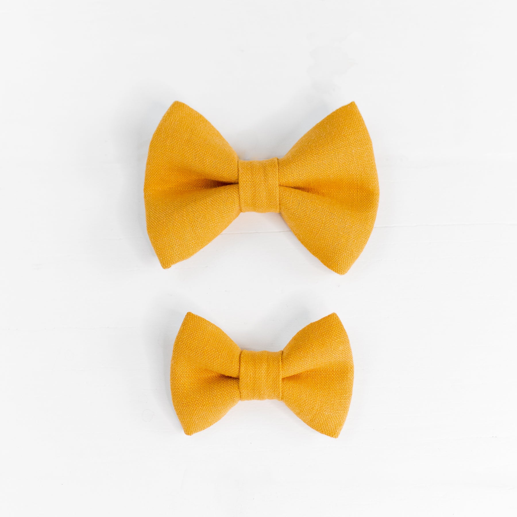 Two linen dog bow ties in mustard yellow.