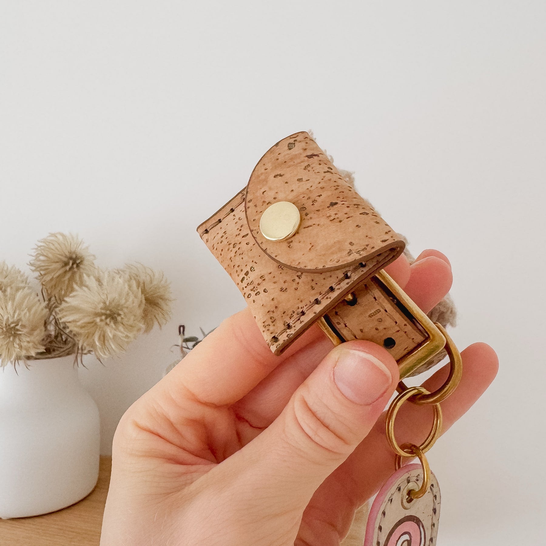 Apple AirTag holder for dogs in brown cork leather held by a hand.