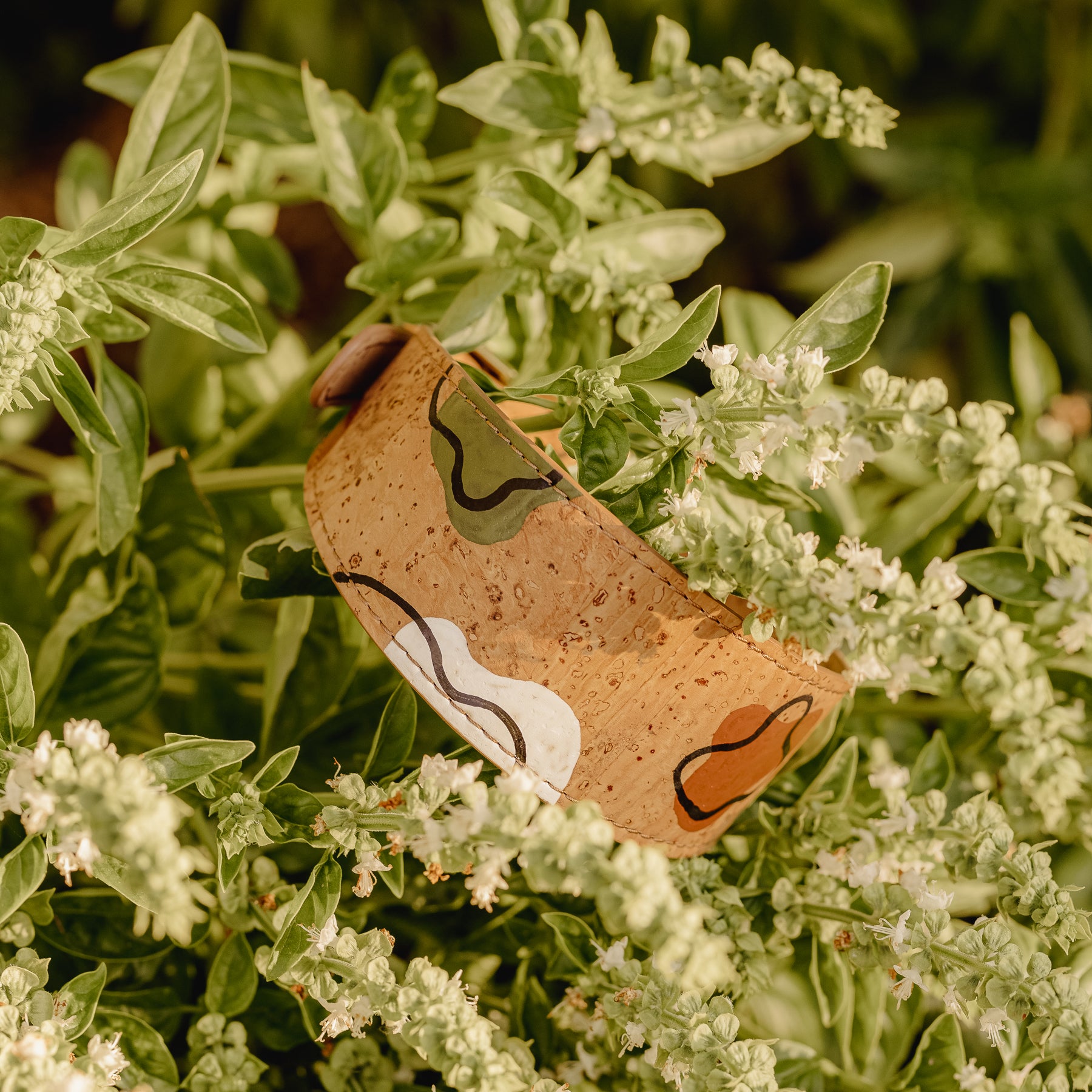 hand-painted soft brown cork leather dog collar on green branch with white flowers