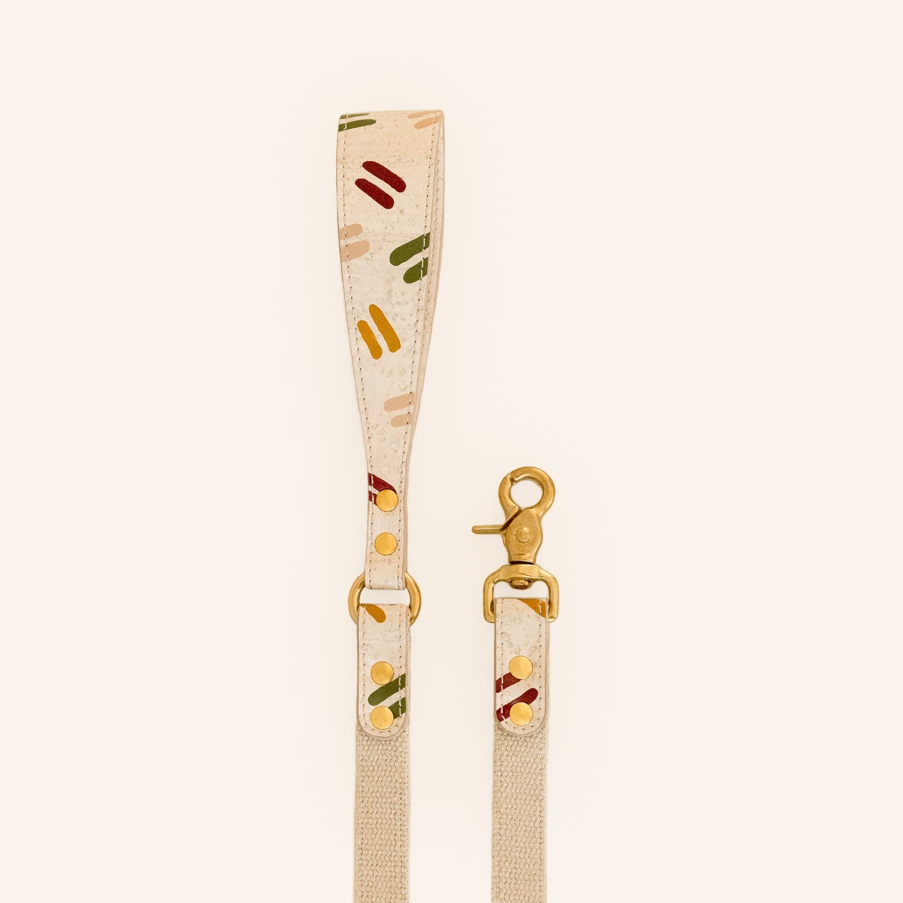 Beige dog leash with colorful pattern and brass details, front view.