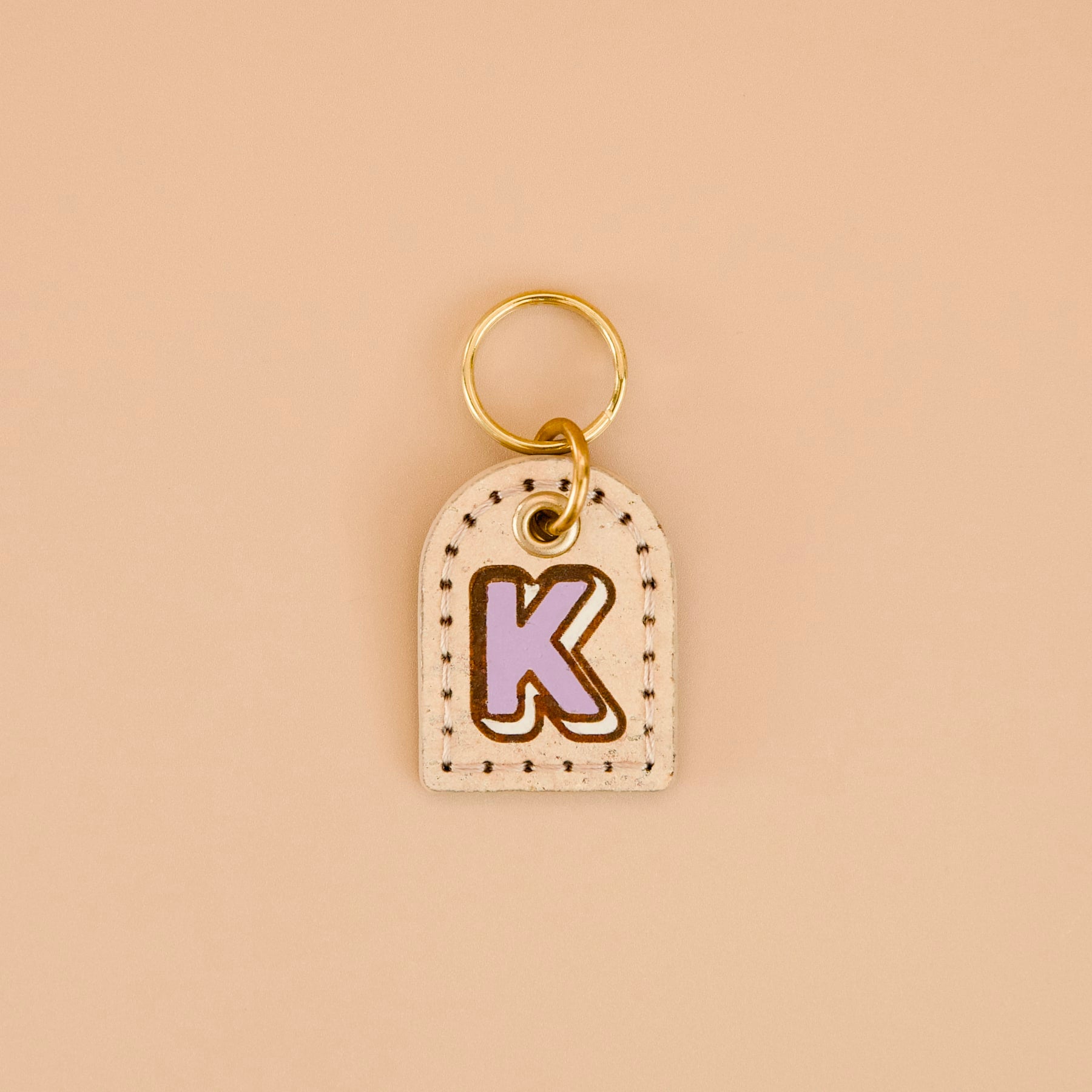 Beige cream cork leather dog ID tag with purple monogram “K”, hand-painted edges, brass split ring