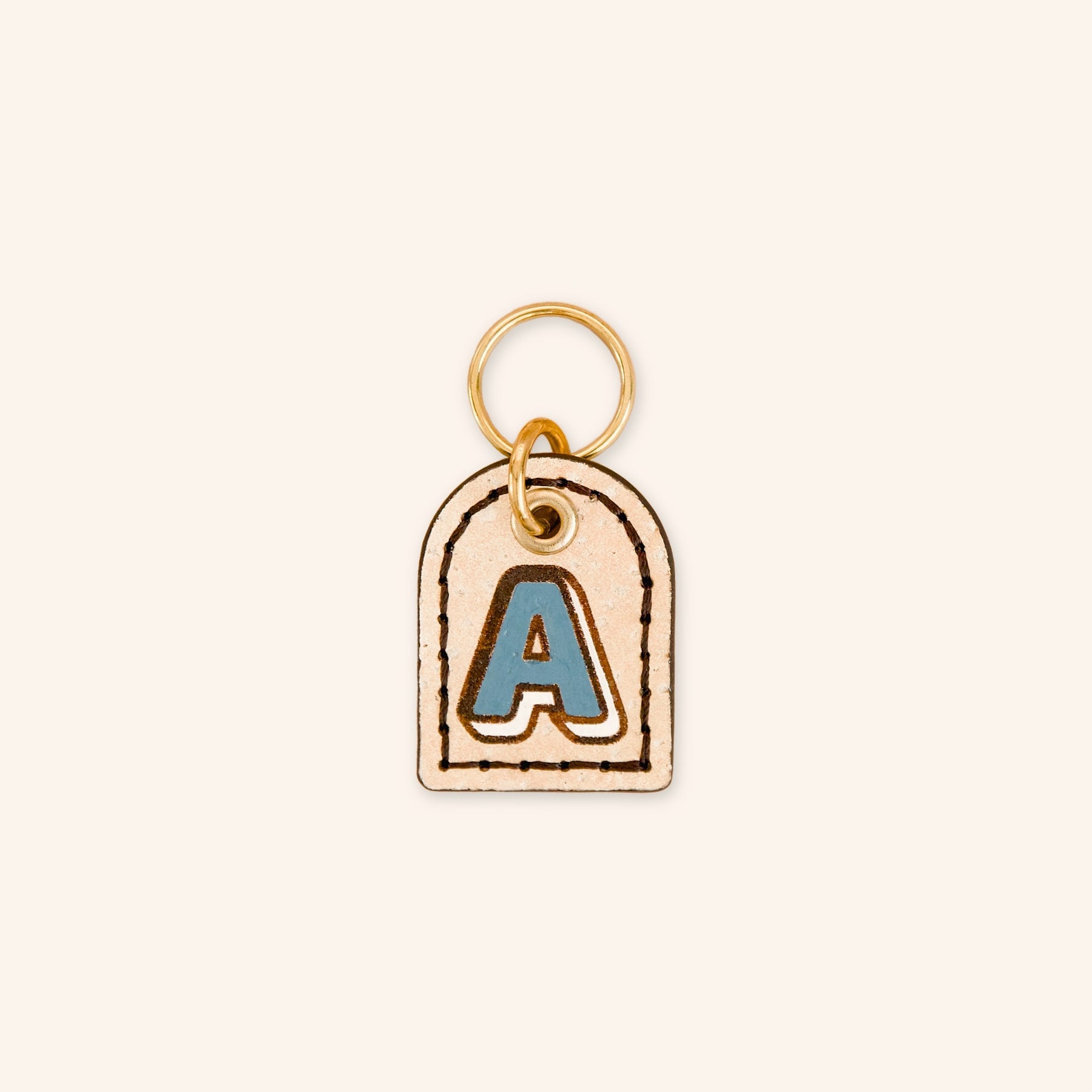 Custom dog tag with letter 'A' in blue on cream beige cork leather.