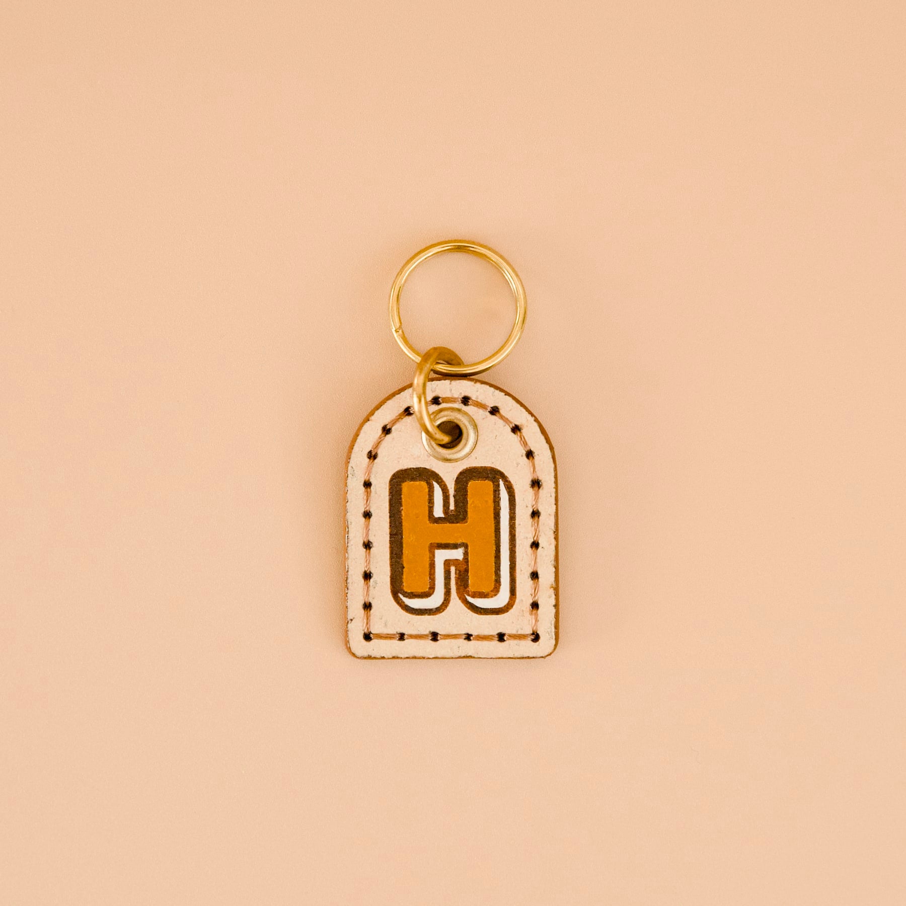 Beige cream cork leather dog ID tag with mustard yellow monogram “H”, mocha brown edges, brass split ring