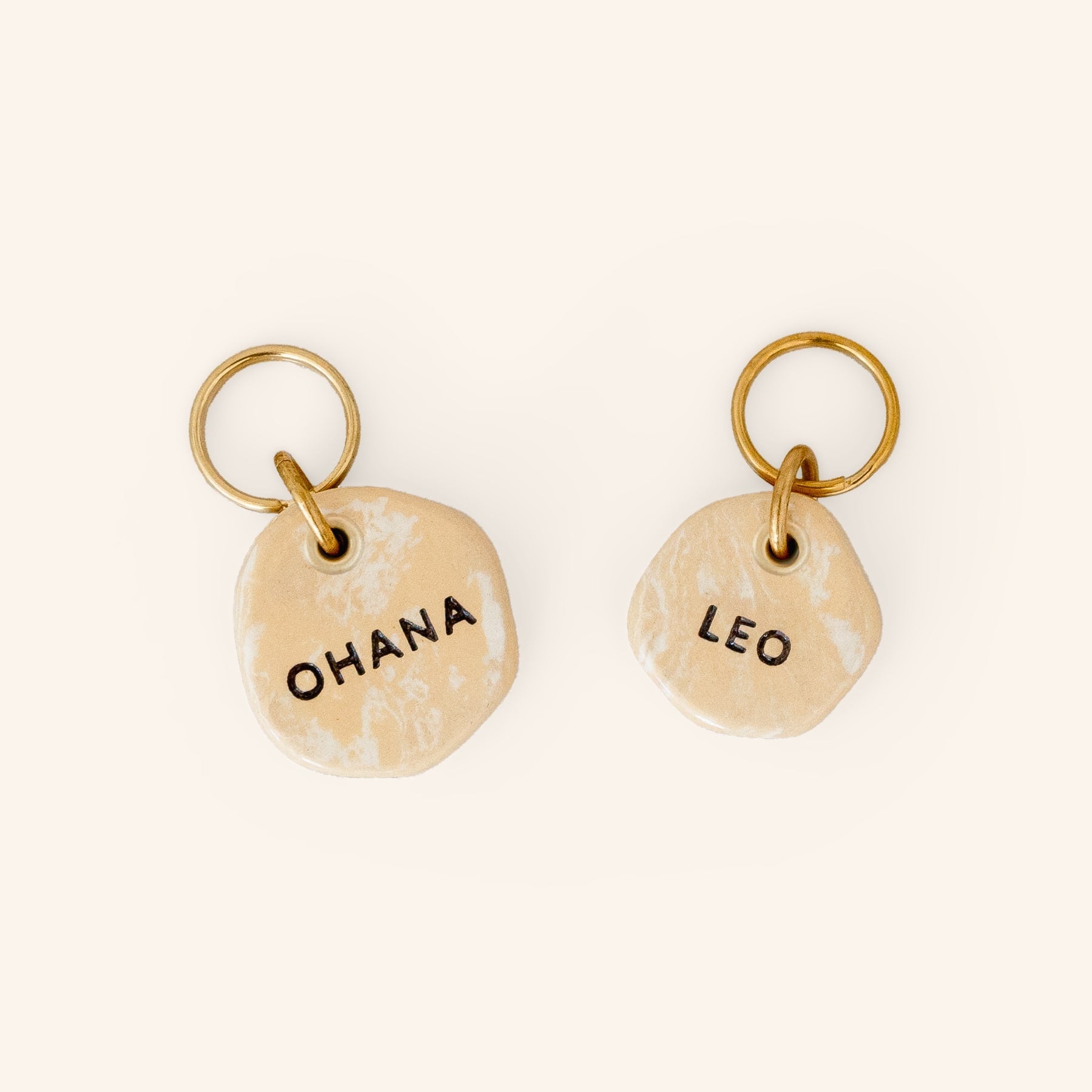 two personalised dog name tags in beige travertine inspired earth clay, close-up